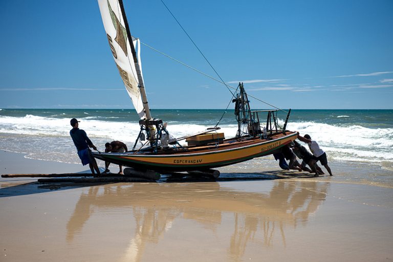imagem de jangada sendo empurrada na praia