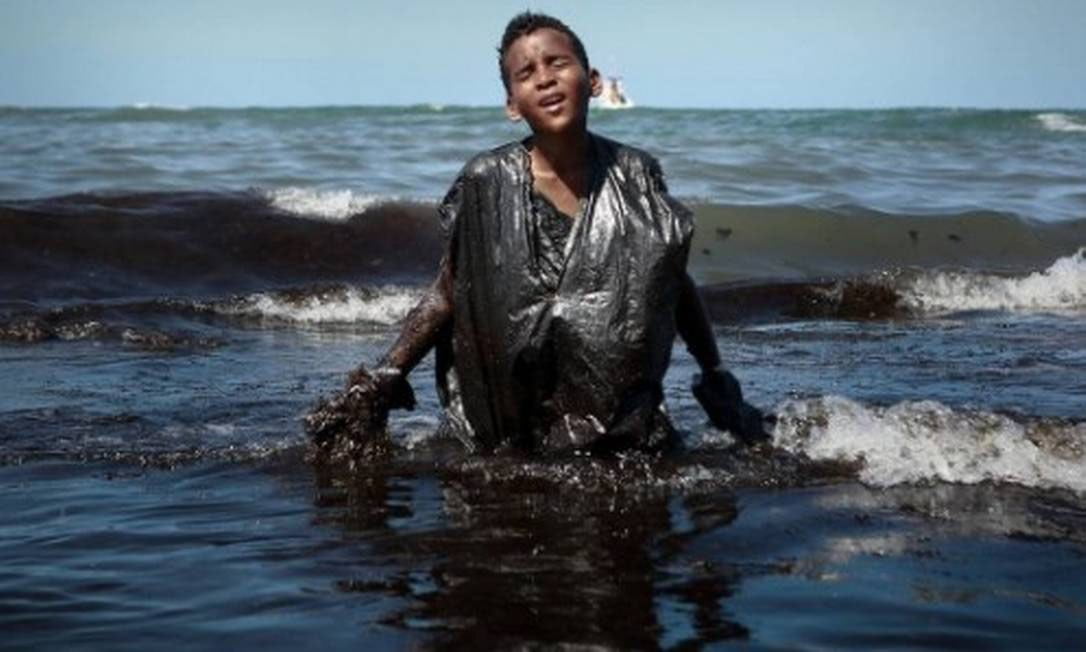 Imagem de menino sujo de óleo saindo do mar