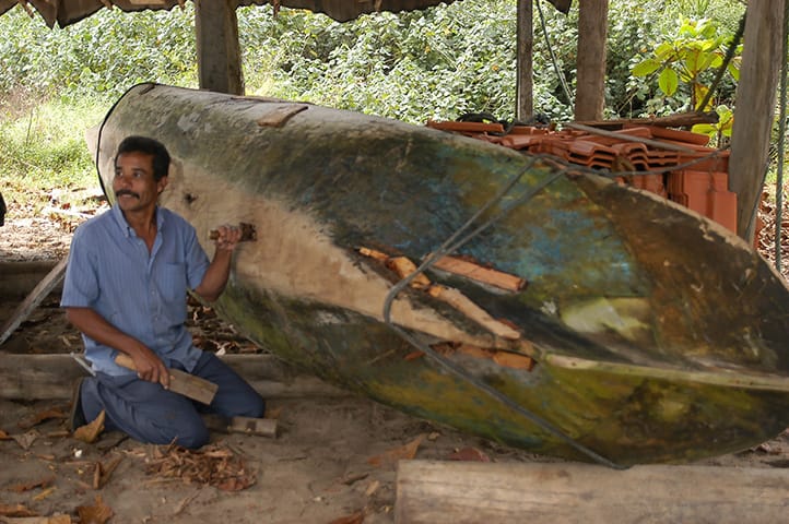 artesão conserta canoa em Pouso da Cajaíba